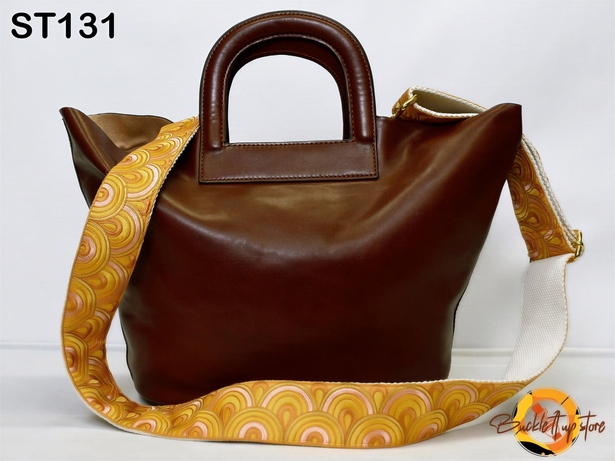 A brown leather handbag with a patterned strap and a handle, displayed against a white background.