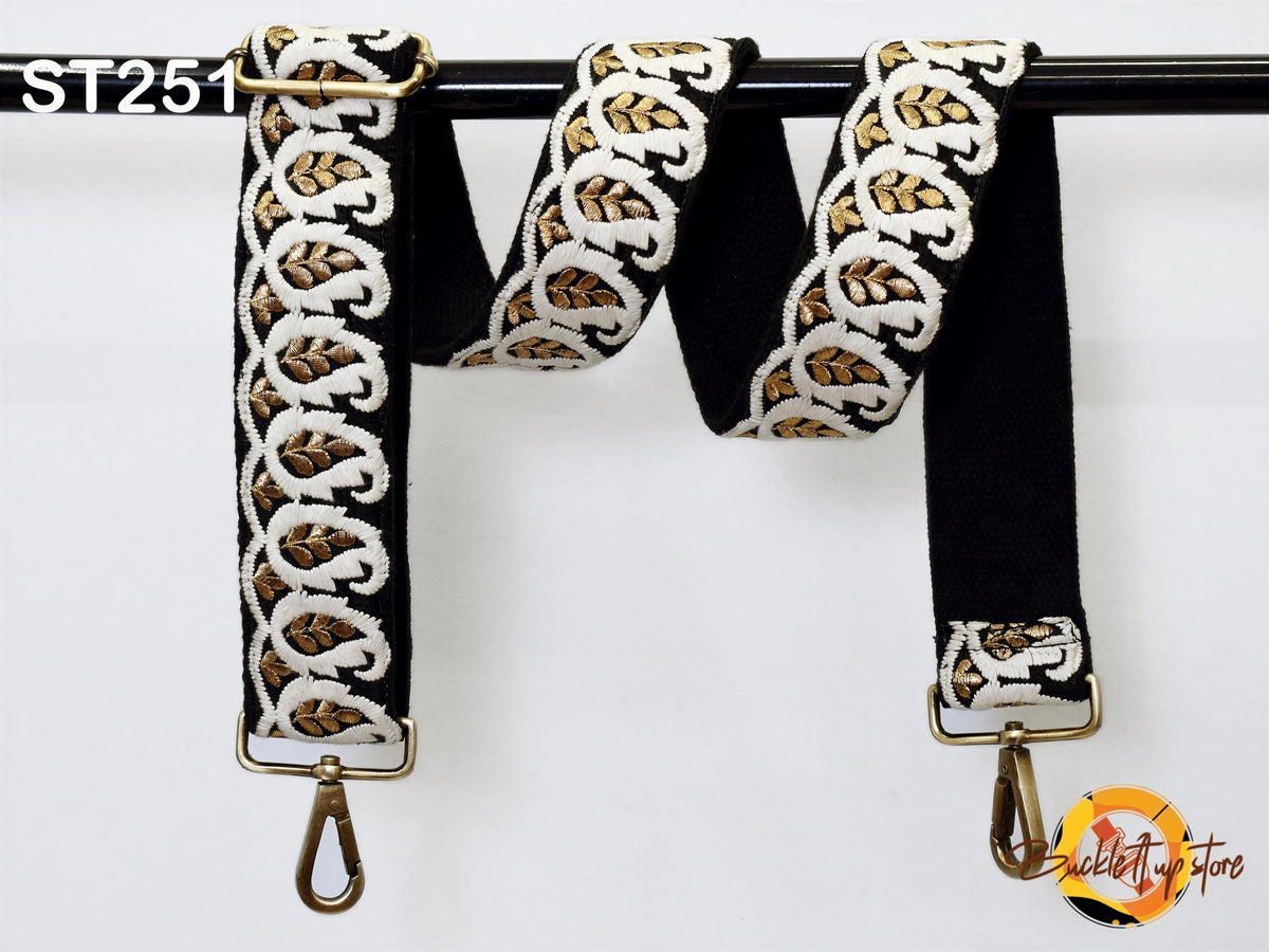 A black and gold embroidered strap with a gold metal hook attached to it, hanging on a black rod.