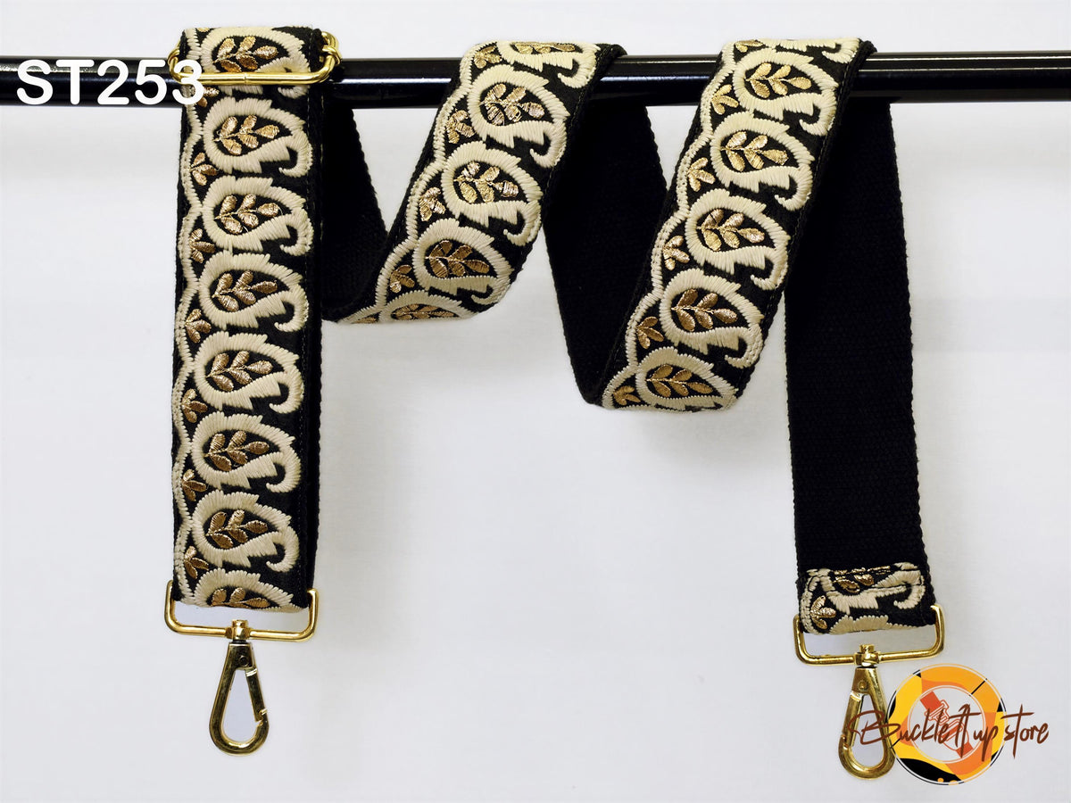 A black and gold patterned strap with a gold metal hook attached to it, hanging on a black pole.