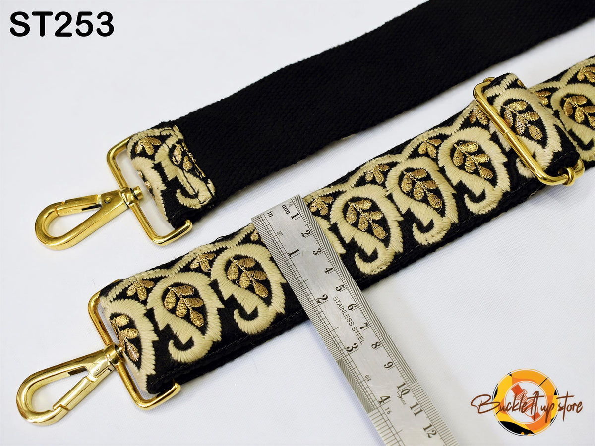 a black strap with gold embroidered patterns, and a ruler is placed next to it, indicating the strap's length.