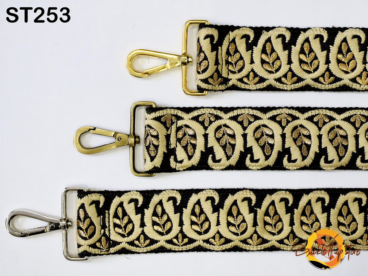three straps with a paisley pattern in gold and black colors. The straps appear to be made of fabric and have metal hooks or buckles attached to them.