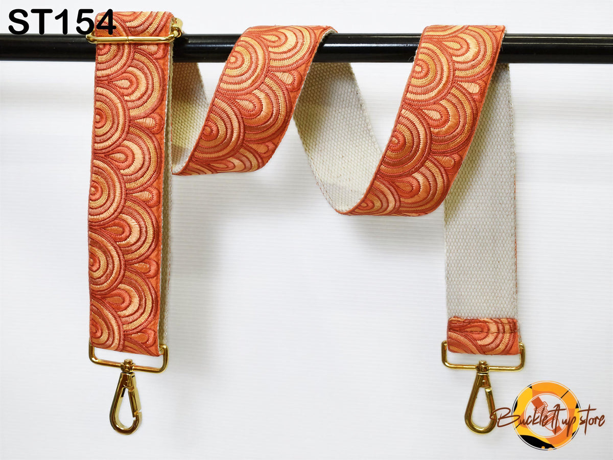 a colorful, patterned strap with a gold metal buckle attached to a black metal bar.