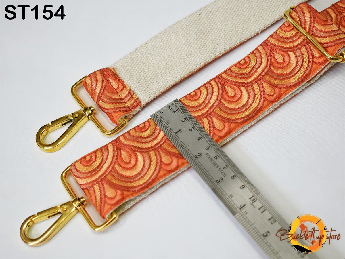 a strap with a patterned design, a ruler, and a gold-colored metal clasp.