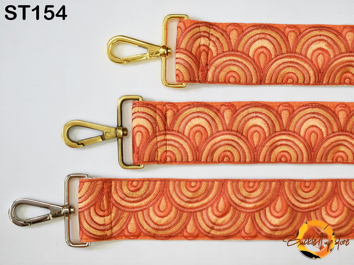 three straps with a repeating pattern of orange and yellow circles, each with a metal clasp and a metal loop. The straps appear to be made of fabric and are arranged in a row.