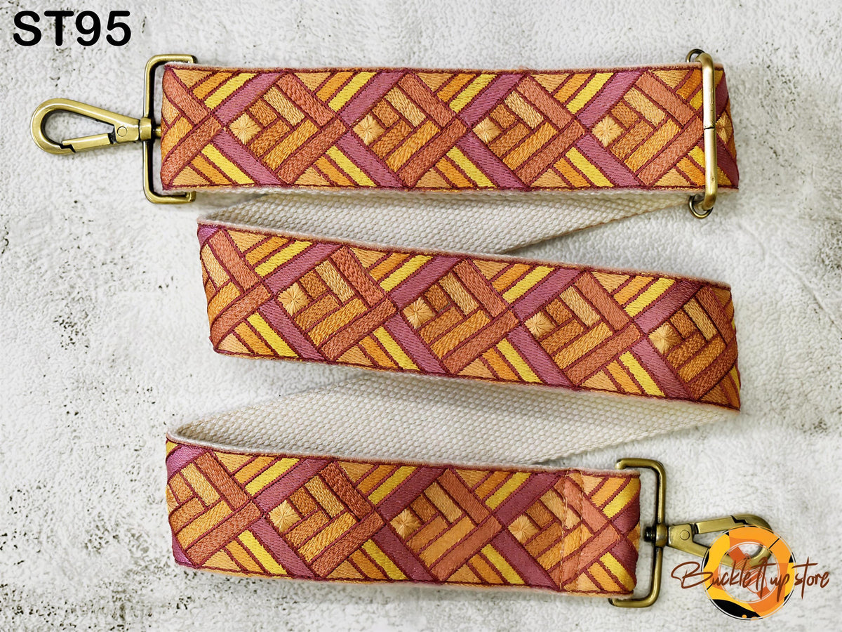 a colorful strap with a geometric pattern in shades of orange, pink, and yellow. The strap appears to be made of fabric and is attached to a metal clasp.