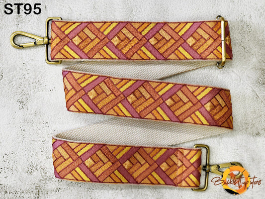 a colorful strap with a geometric pattern in shades of orange, pink, and yellow. The strap appears to be made of fabric and is attached to a metal clasp.