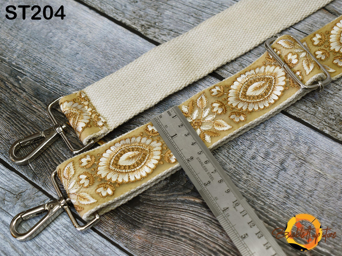 a beige strap with a floral pattern, resting on a wooden surface. A metal ruler is placed next to the strap, and a clasp is visible on the strap.