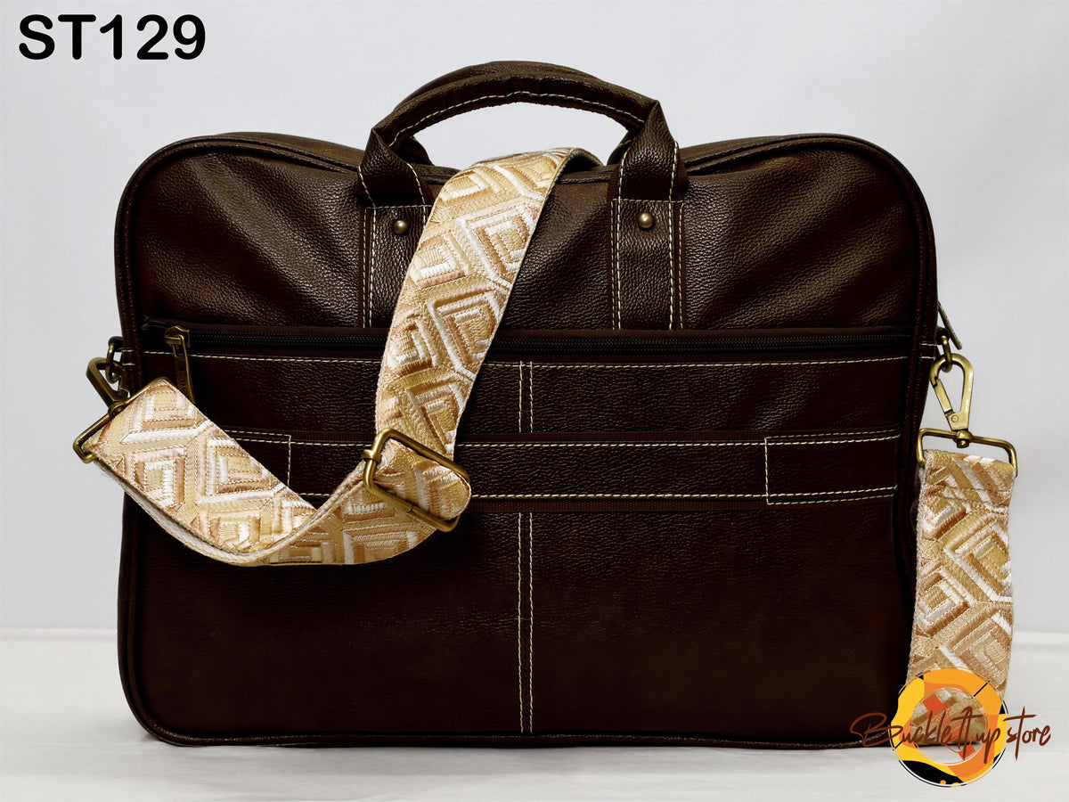 A brown leather briefcase with a patterned strap and handle, sitting on a white surface.