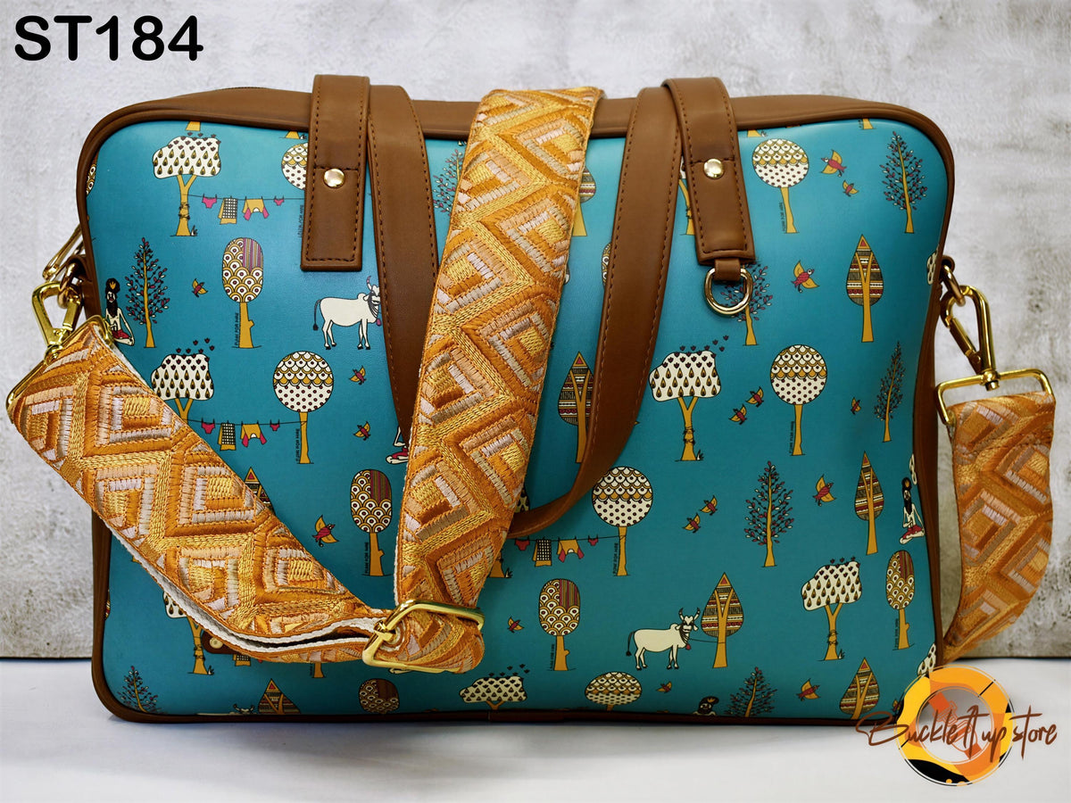 A colorful handbag with a pattern of trees and animals printed on it, featuring a teal background with orange and yellow accents.