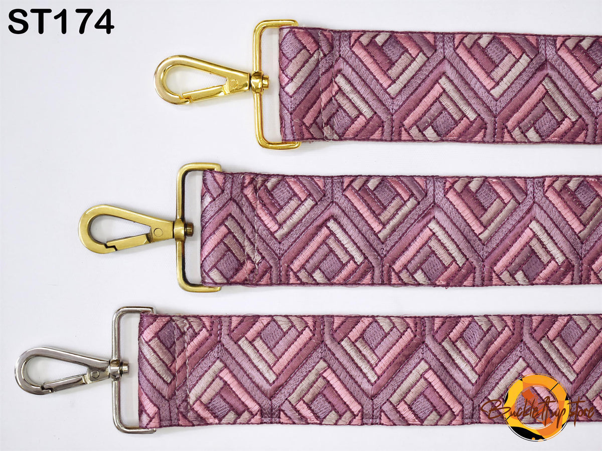 three straps with a geometric pattern in shades of pink and purple. The straps have gold buckles and metal clips, and the straps appear to be made of a shiny material.