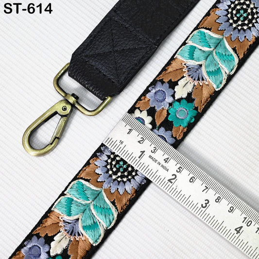 a black strap with a floral pattern and a metal ruler placed on a white surface.