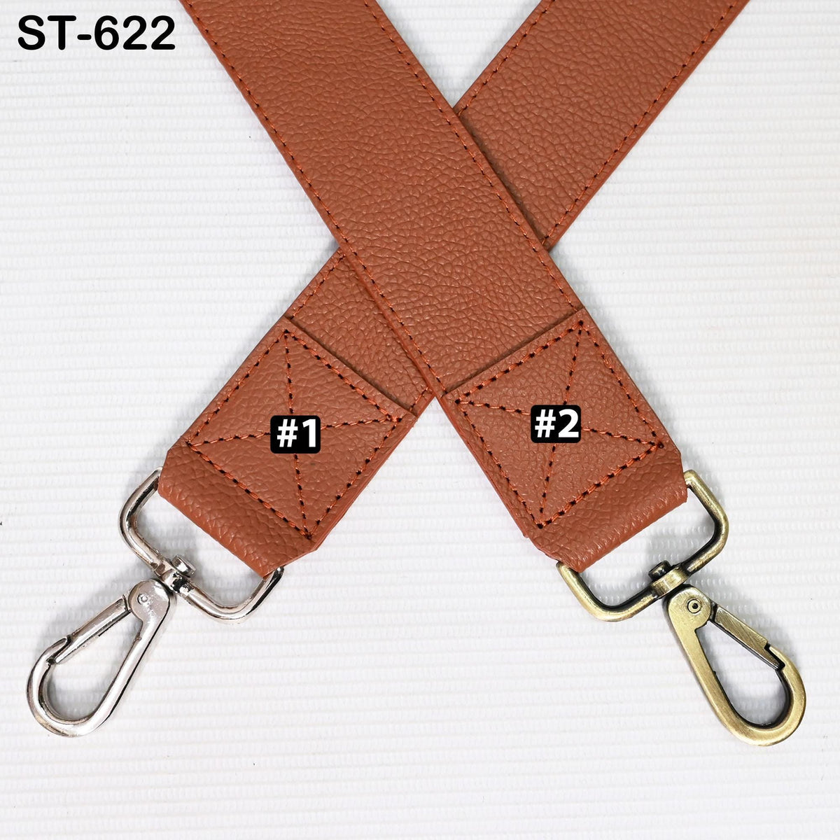 a brown leather strap with two metal hooks attached to it, placed diagonally across a white background.