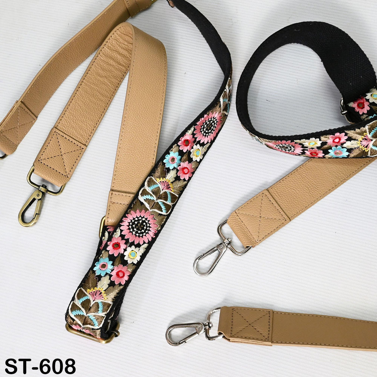 a collection of beige leather straps with floral embroidery, including a large floral strap and smaller straps with similar designs.