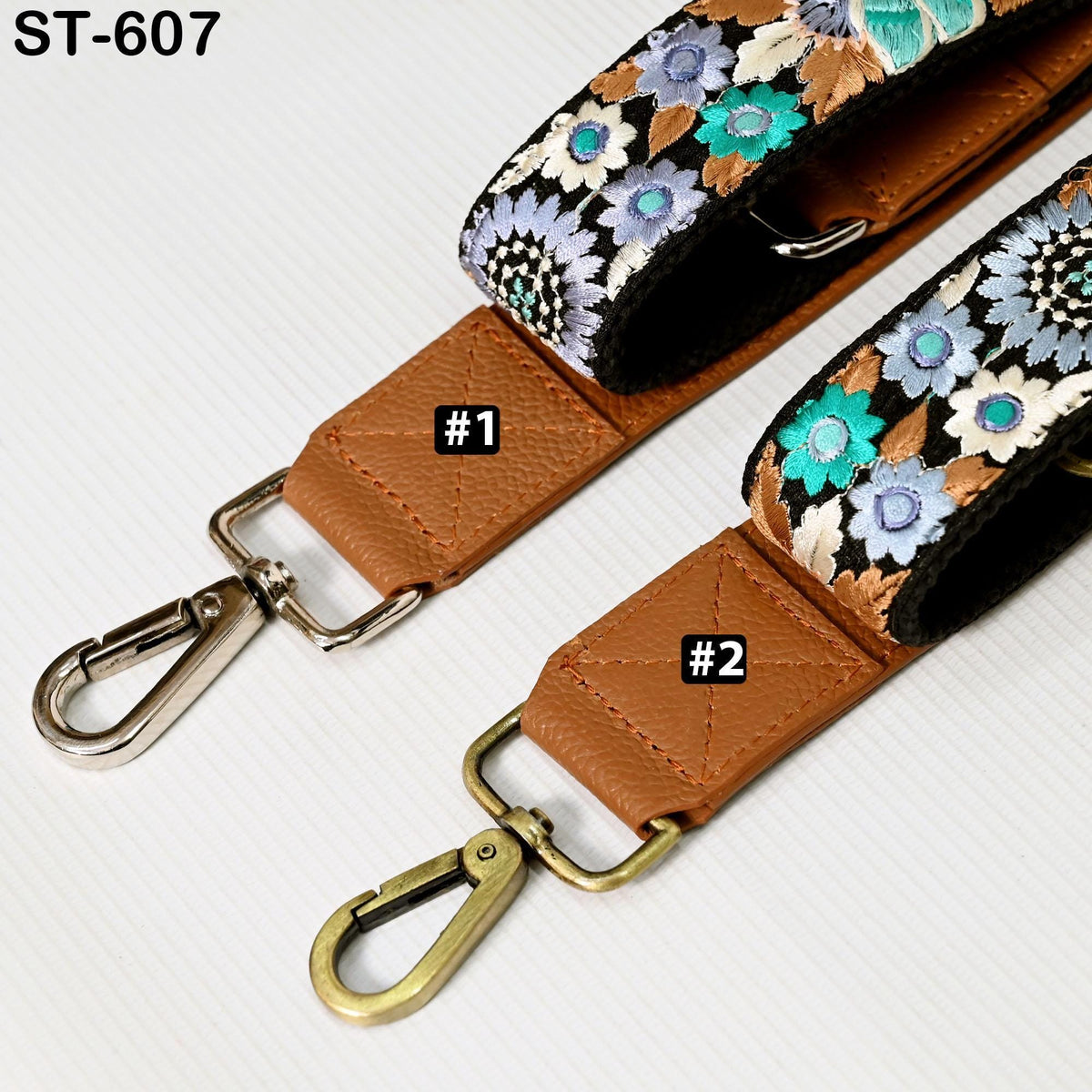two leather straps with floral patterns, one with a metal clasp and the other with a gold clasp.