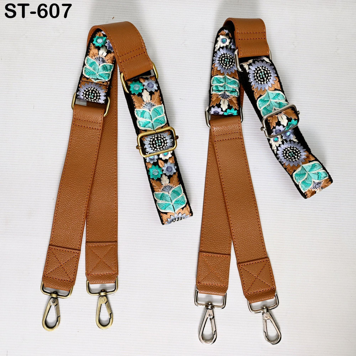 two brown leather straps with floral embroidery, each with metal hooks and buckles.