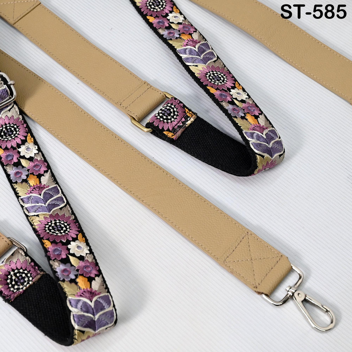 a beige strap with a floral pattern, featuring a metal clasp and a metal hook.