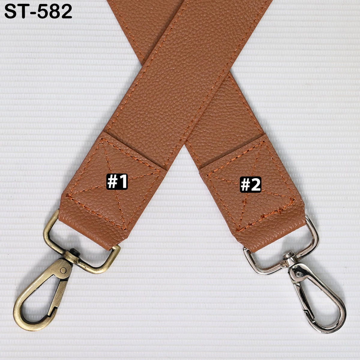 a brown leather strap with two metal hooks attached to it, placed on a white surface.