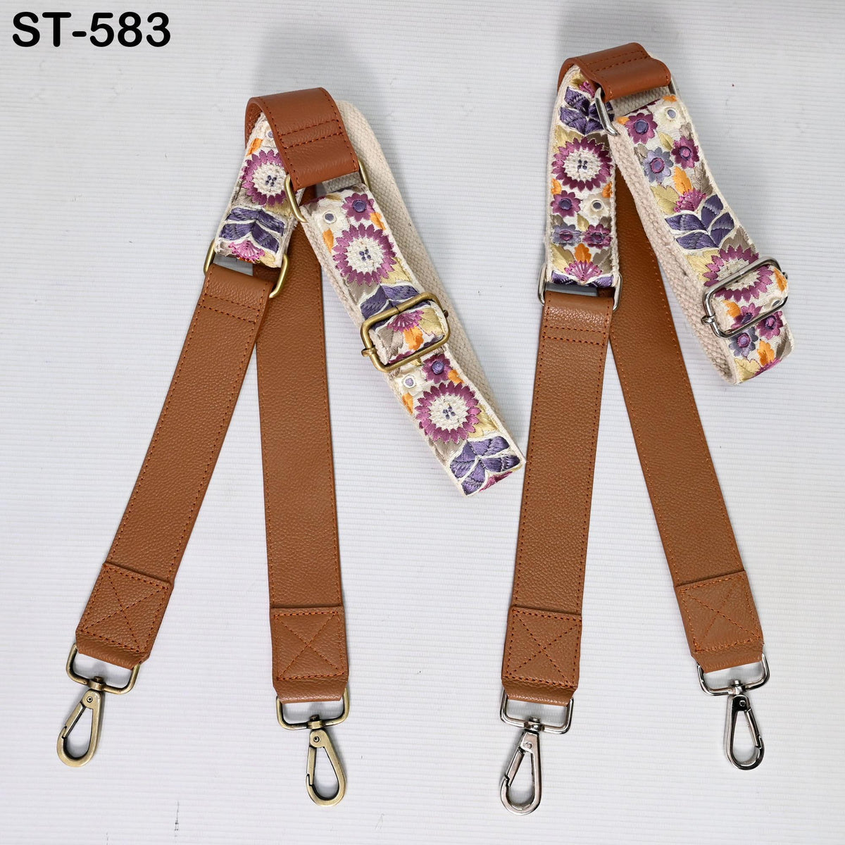 a pair of brown leather straps with floral patterns, each with a metal hook at the end. The straps appear to be designed for use as crossbody straps or shoulder bags.