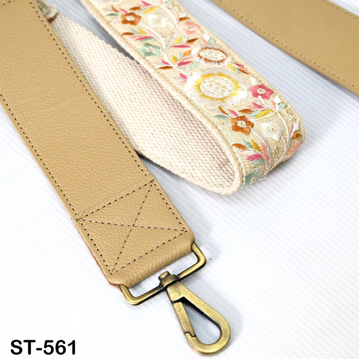 A tan leather strap with a floral pattern and a metal clasp is shown in the image.